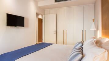 Un dormitorio con una cama, un televisor montado en la pared y un armario con puertas correderas.