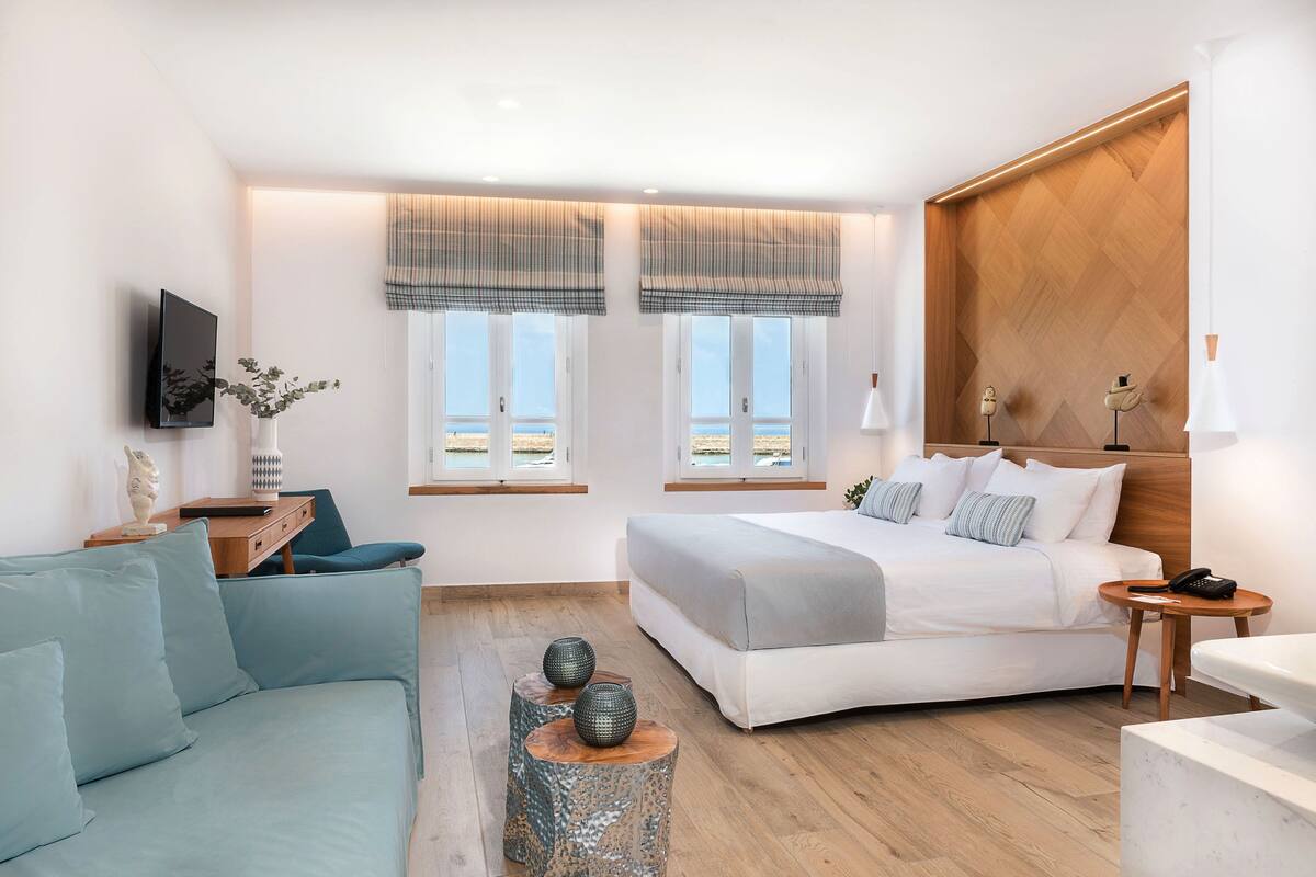 Una camera da letto moderna con un letto, un divano, una TV e vista sulla spiaggia.