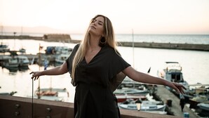 A person standing on a balcony with a view of a marina and boats. - Avra Apartments Venetian Harbour (Chania)
