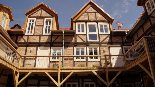 A traditional half-timbered building with multiple windows, a balcony, and a satellite dish.