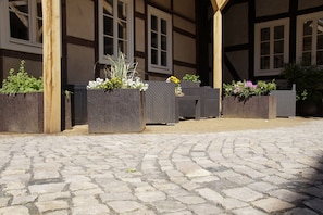 A courtyard with stone paving, wooden beams, and flower planters. - Fachwerkresidenz Deuterscher Hof (Quedlinburg)