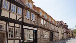 A row of traditional half-timbered buildings with large windows and a cobblestone street.