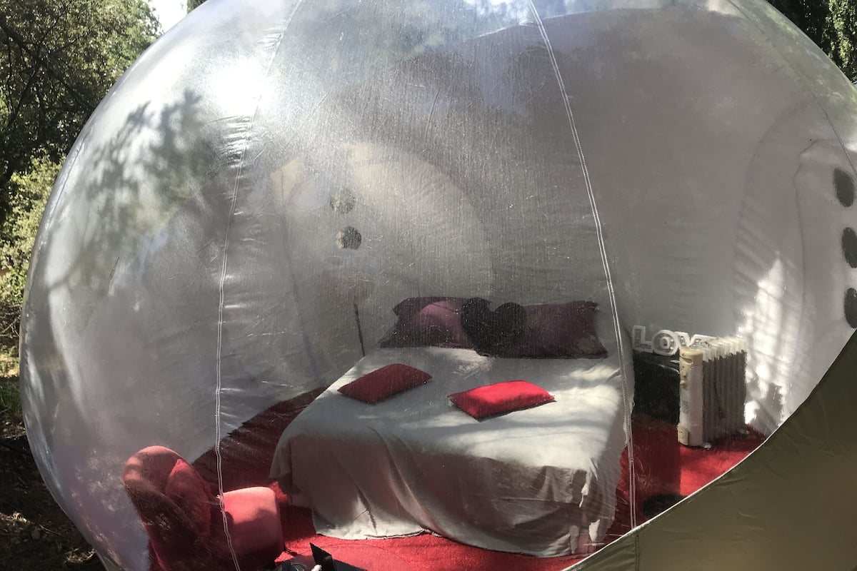 Una habitación en forma de cúpula transparente con una cama, almohadas y un radiador.