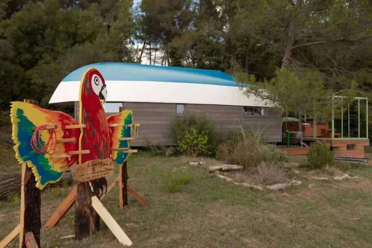 Una escultura de un guacamayo colorido frente a una casa moderna con techo azul.