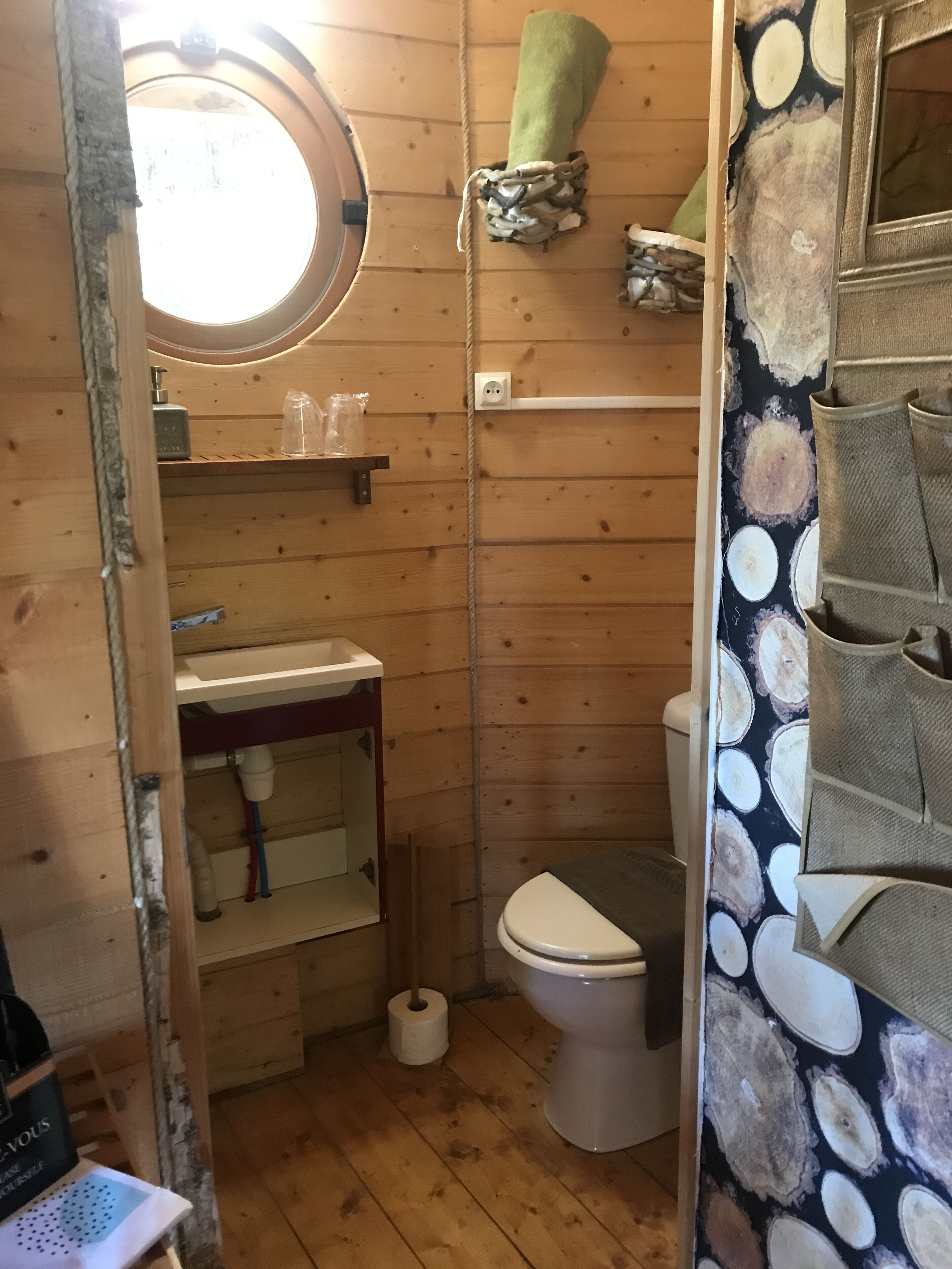 Un baño pequeño de madera con inodoro, lavamanos y zona de ducha.
