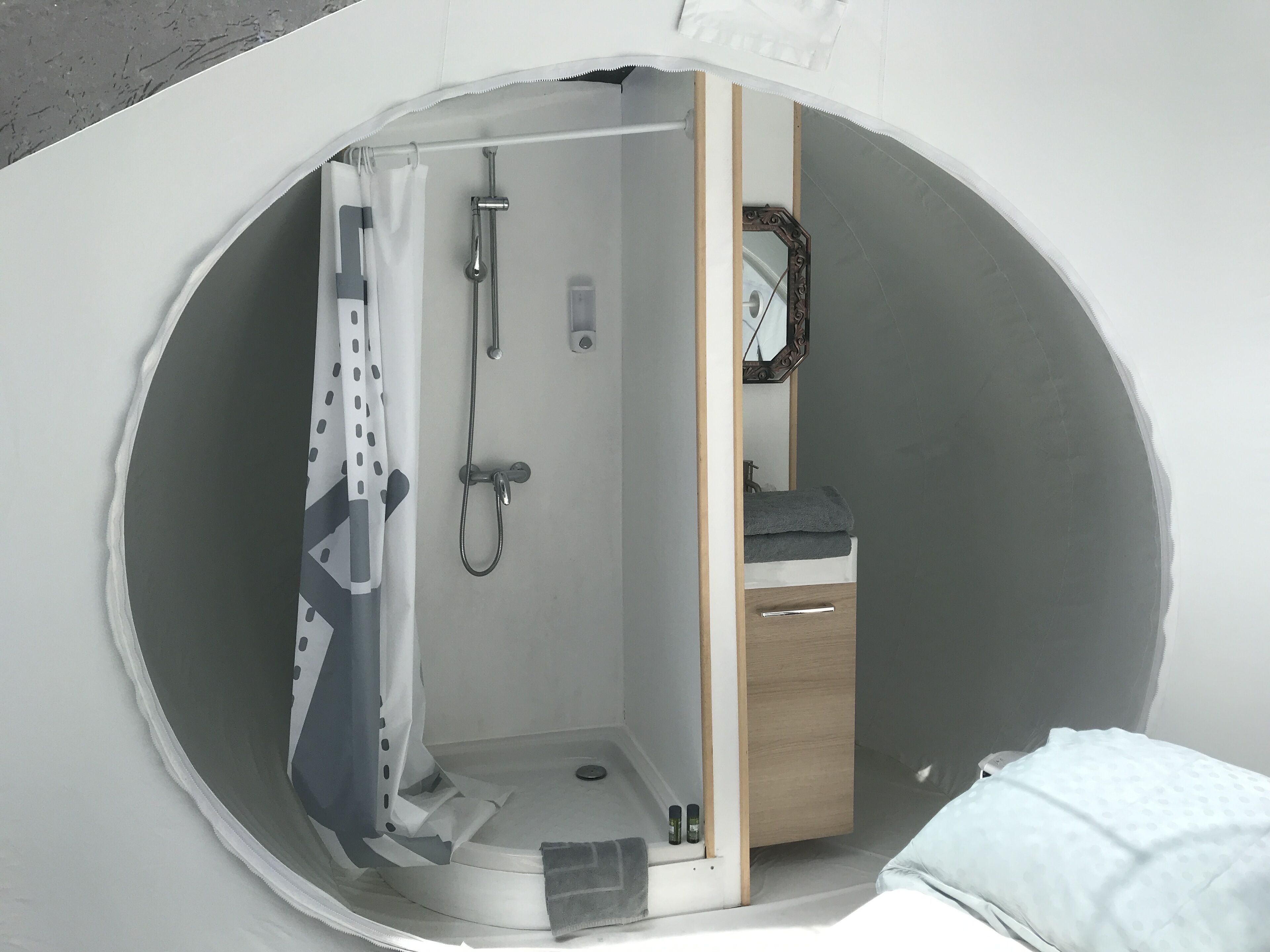 Una ventana circular con zona de ducha, un mueble de madera y un espejo.