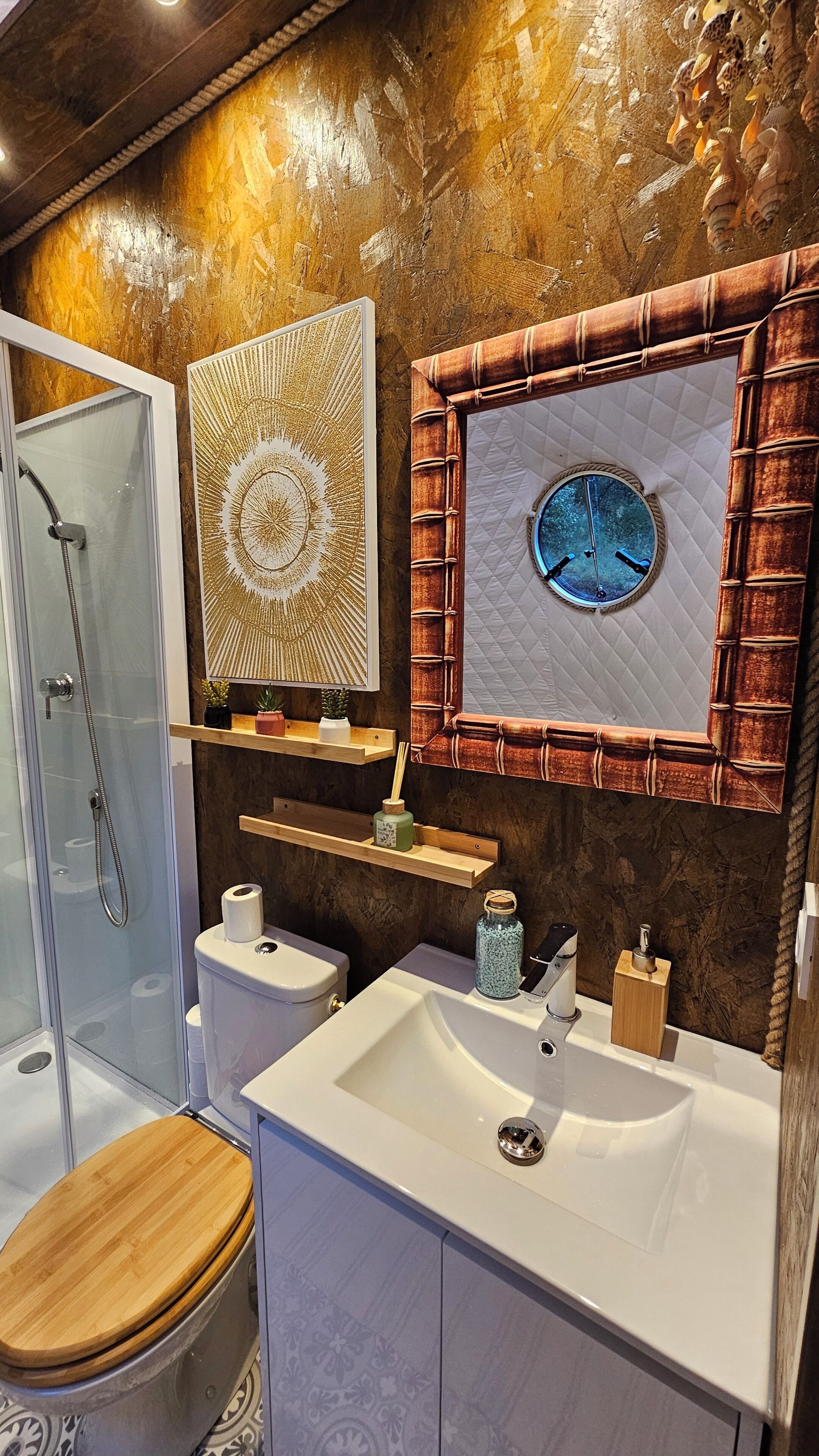 Une salle de bain avec une douche à parois de verre, un lavabo blanc, des toilettes et des éléments décoratifs sur les murs.
