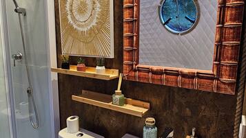 Une salle de bain avec une douche à parois de verre, un lavabo blanc, des toilettes et des éléments décoratifs sur les murs.