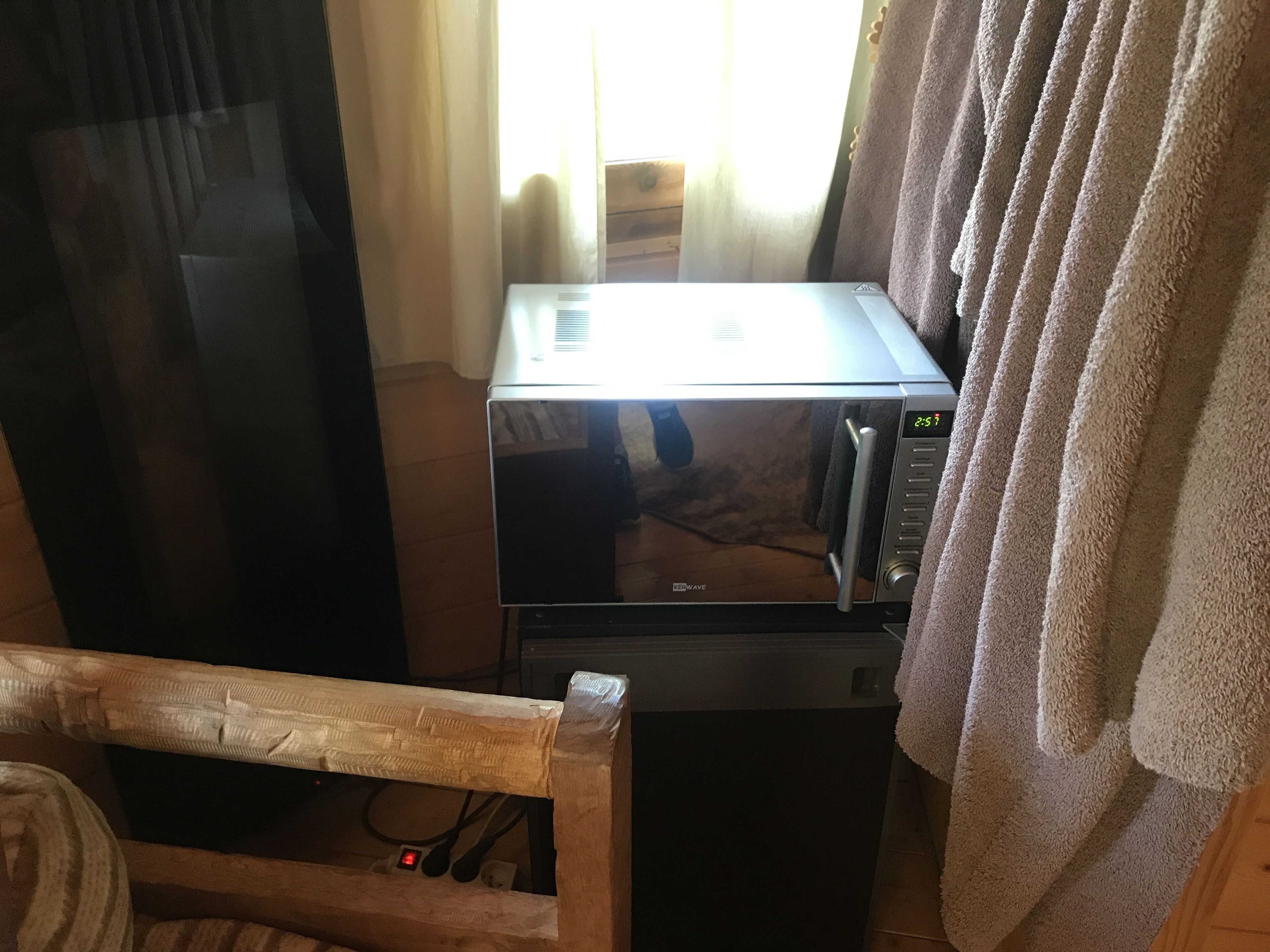 Un four à micro-ondes est posé sur une table en bois, et une serviette est suspendue sur le côté droit.
