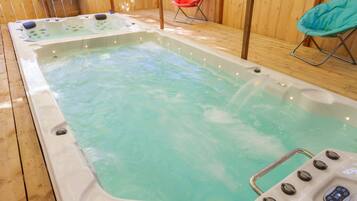 Un jacuzzi con controles, rodeado de piso de madera y dos sillas.