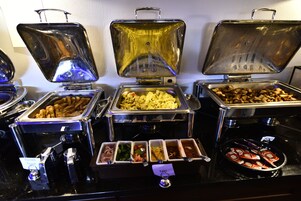 Un bufé con diversos alimentos, entre ellos tostadas francesas, huevos y otras preparaciones.