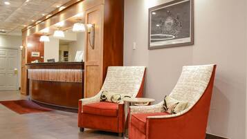 A lobby with two red armchairs, a reception desk, and a framed emblem on the wall.