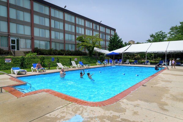 A swimming pool with lounge chairs and a building in the background.