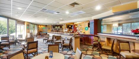 Un vestíbulo de hotel con mesa de billar, zona de comedor y bar.