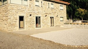 Un bâtiment en pierre avec un toit en tuiles, de nombreuses fenêtres et une allée gravillonnée.