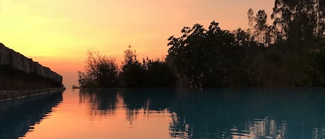 Una piscina al aire libre, una piscina con borde infinito, tumbonas