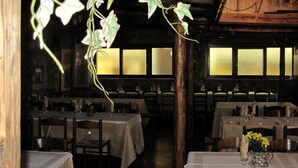 Un restaurante con mesas dispuestas para comer, vigas de madera en el techo y vistas a través de las ventanas.