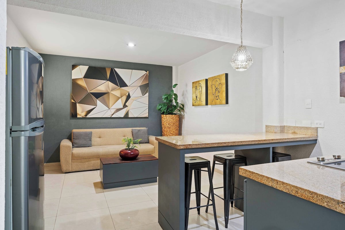 A modern kitchen with a built-in island, bar stools, and a refrigerator.