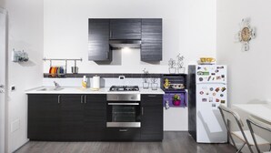 A modern kitchen with dark cabinetry, a stainless steel range, and a white refrigerator. - B&B Sleep & Zupp (Naples)
