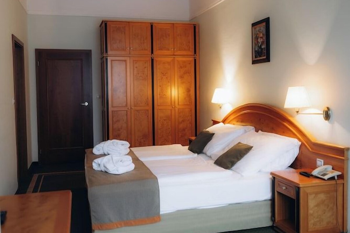 Een hotelkamer met een tweepersoonsbed, twee nachtkastjes, een kledingkast en een plafondventilator.