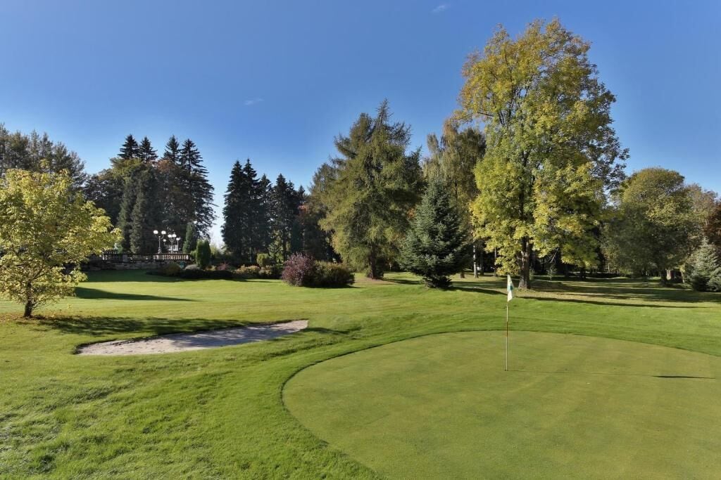 A golf course with a putting green, sand bunkers, and a flagstick.