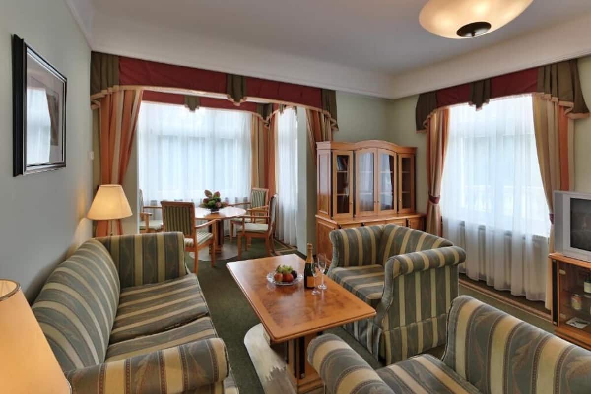 Een woonkamer met gestreepte banken, een houten kast, een eettafel en gordijnen.
