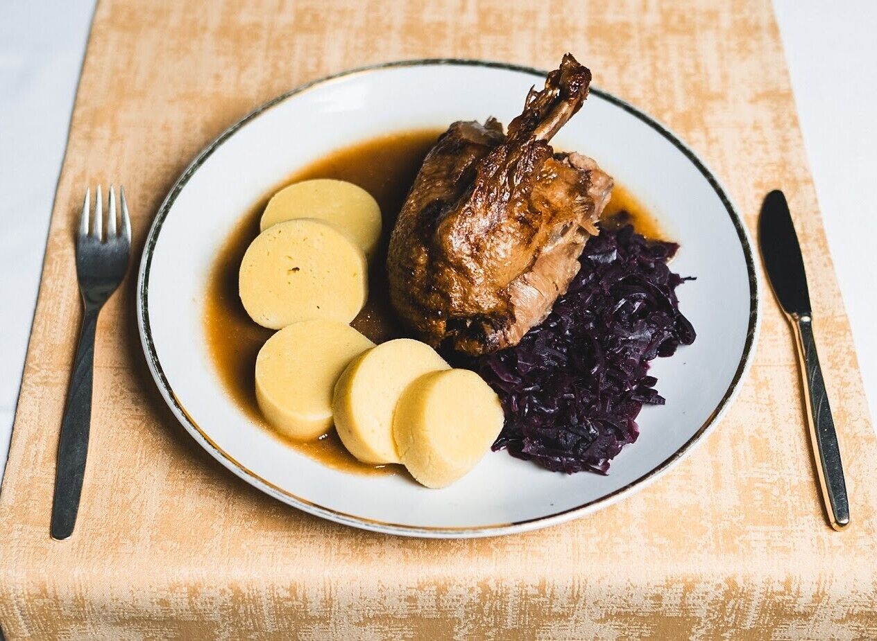Un plato con pato asado, albóndigas y col roja.