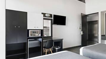 Una habitación de hotel moderna con escritorio, silla, cama y televisor montado en la pared.