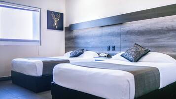 A modern hotel room with two beds, a large window, and a wall-mounted phone.