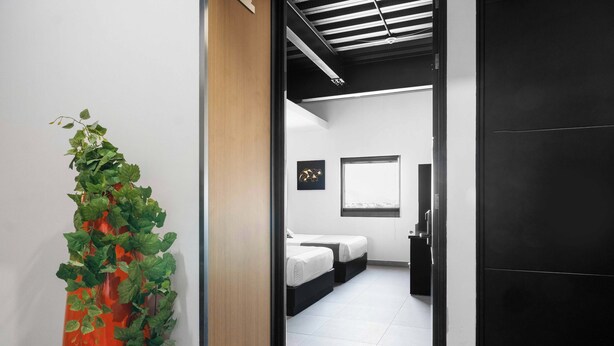 Una habitación de hotel moderna con cama, mesitas de noche y ventana.