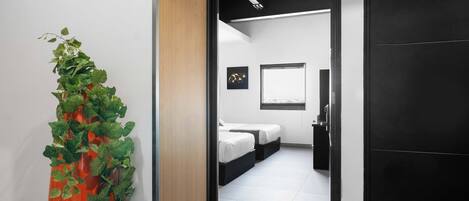 A modern hotel room with a bed, bedside tables, and a window.