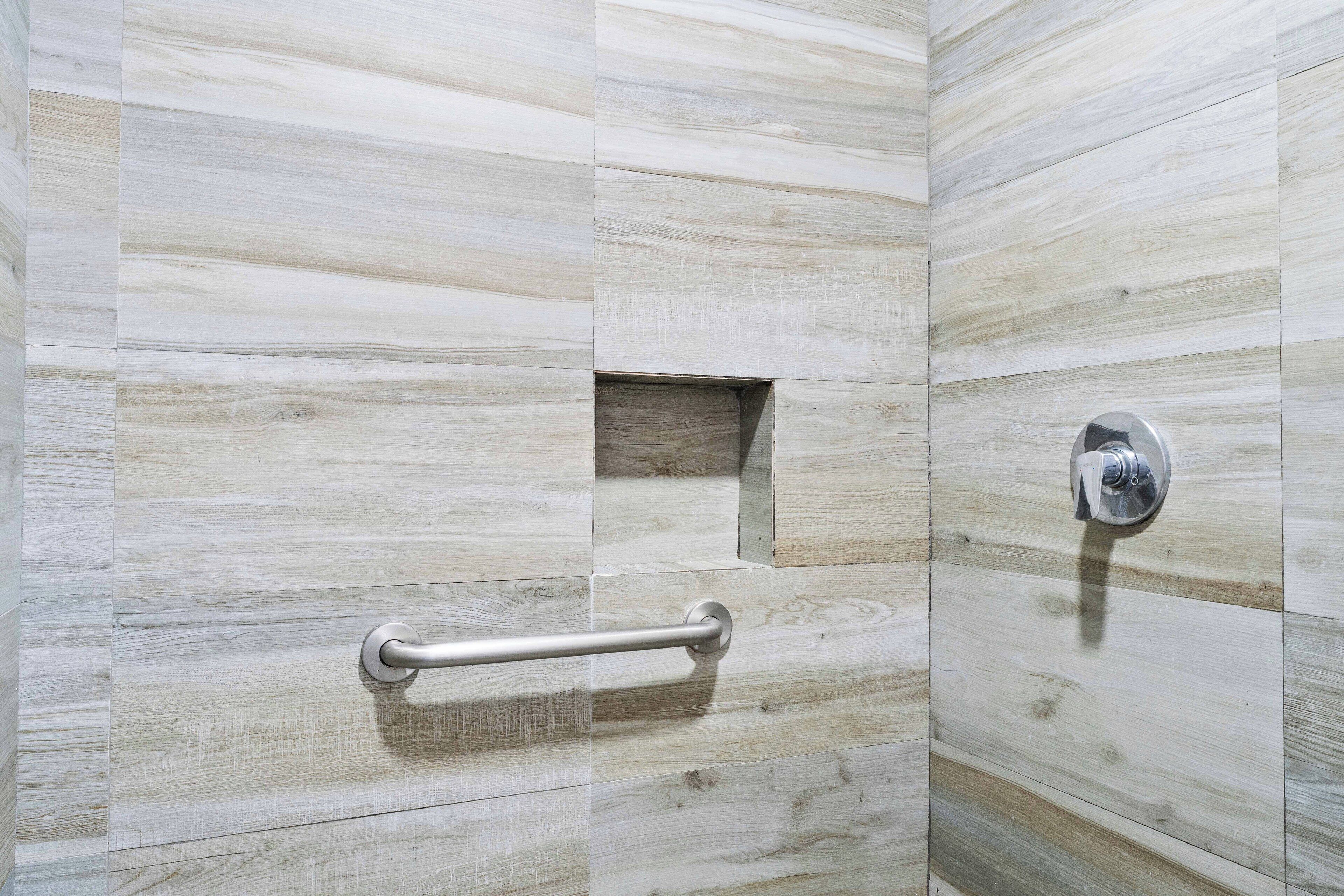 A bathroom with a wooden wall design, a grab bar, and a showerhead.