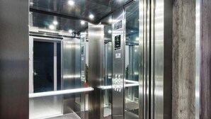 A modern elevator with glass doors and a digital display showing the floor number. - Homesuites Malecon (Culiacán)