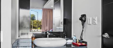 Une salle de bain moderne équipée d’un grand miroir, d’un lavabo, d’un sèche-cheveux et d’un porte-serviettes.