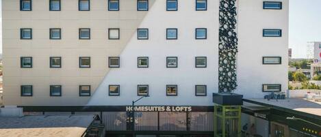 A hotel with a modern facade, multiple windows, and a sign for 'HOMESUITES & LOFTS'.