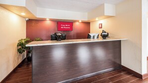 A reception desk with a digital screen, a 'Free Wi-Fi All Rooms' sign, and a security camera. - Red Roof Inn Marion, IN (Marion)