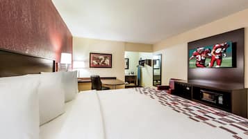 A hotel room with a large bed, a desk, a chair, a television, and a mirror.