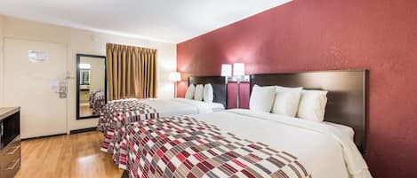 Une chambre d’hôtel avec un grand lit, un bureau et un miroir.