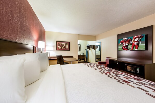 Une chambre d’hôtel avec un grand lit, un bureau, une télévision et un four à micro-ondes.