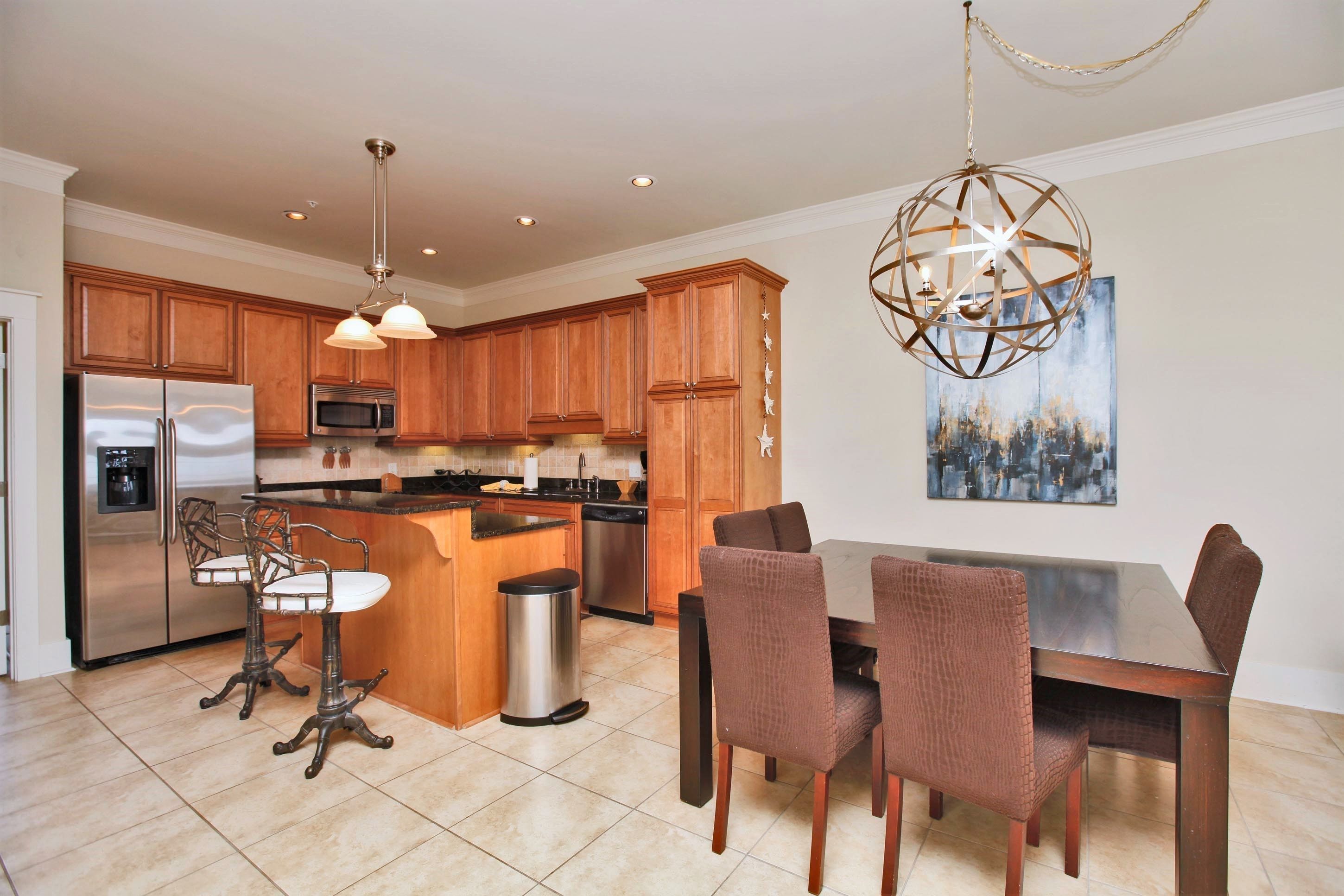 A modern kitchen with wooden cabinets, stainless steel appliances, and a dining area with a large island and chairs.
