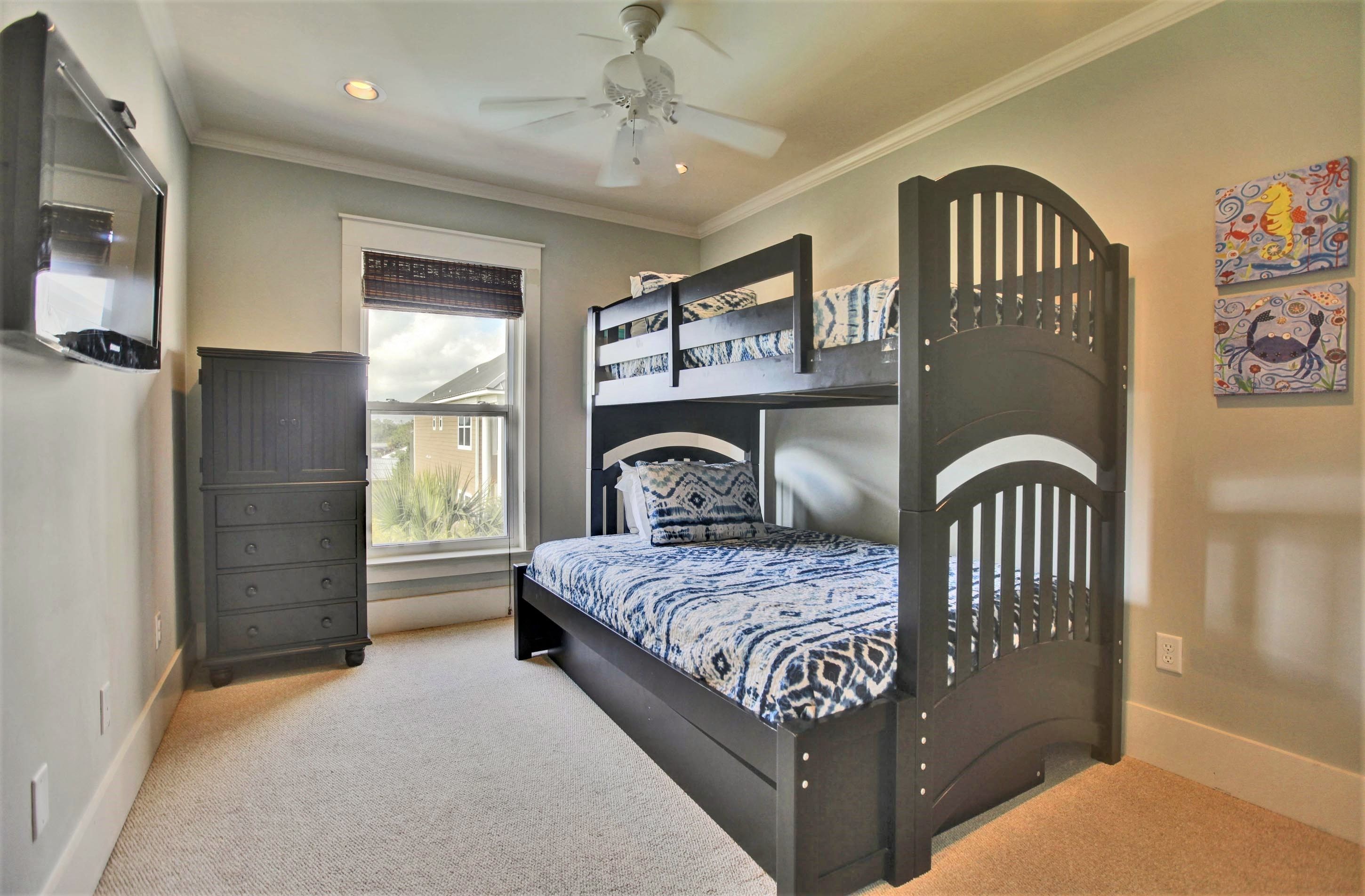 A bedroom with a bunk bed, a dresser, a ceiling fan, and a window with blinds.