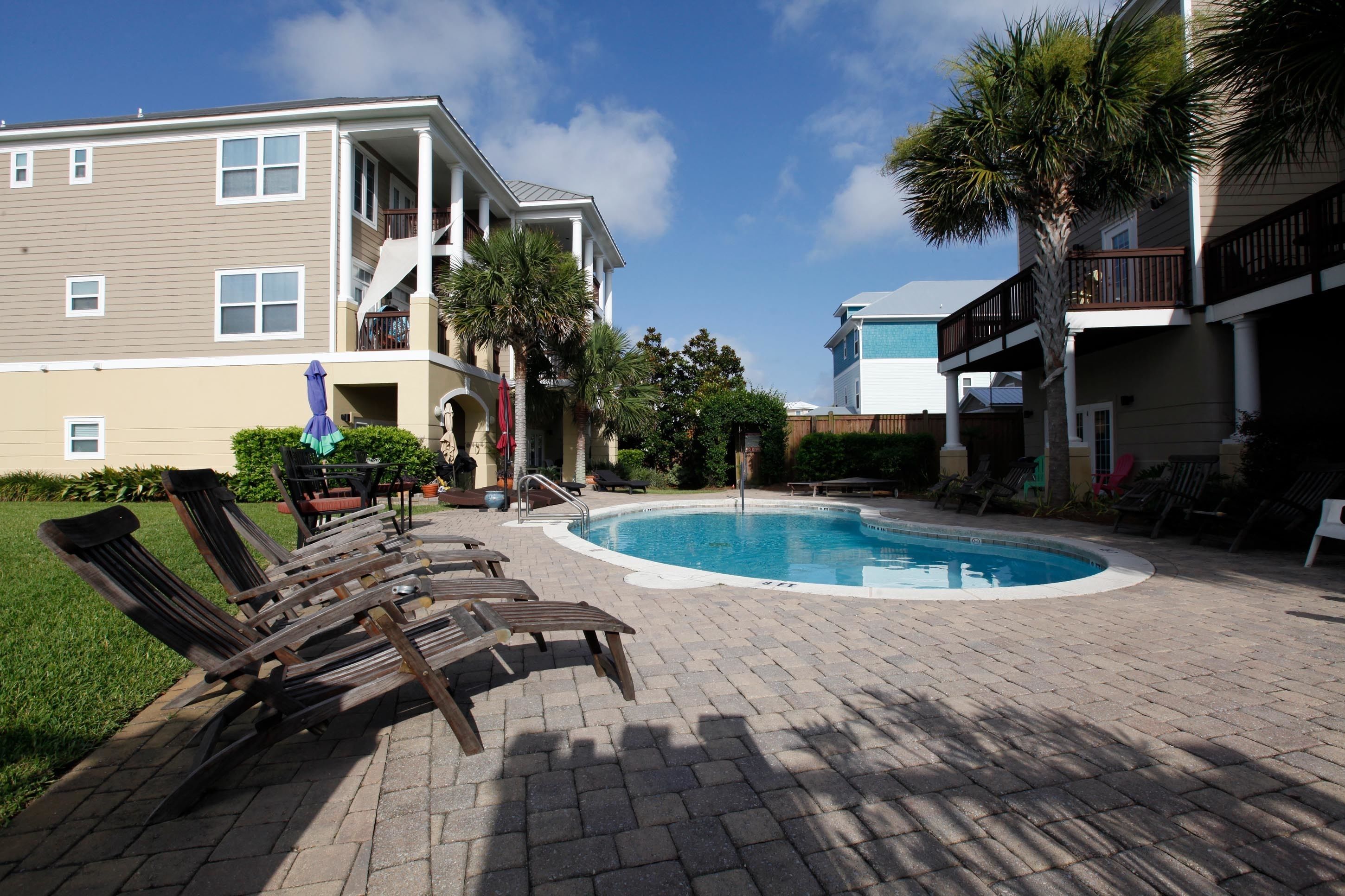A pool area with lounge chairs, a pool, and a building with balconies.