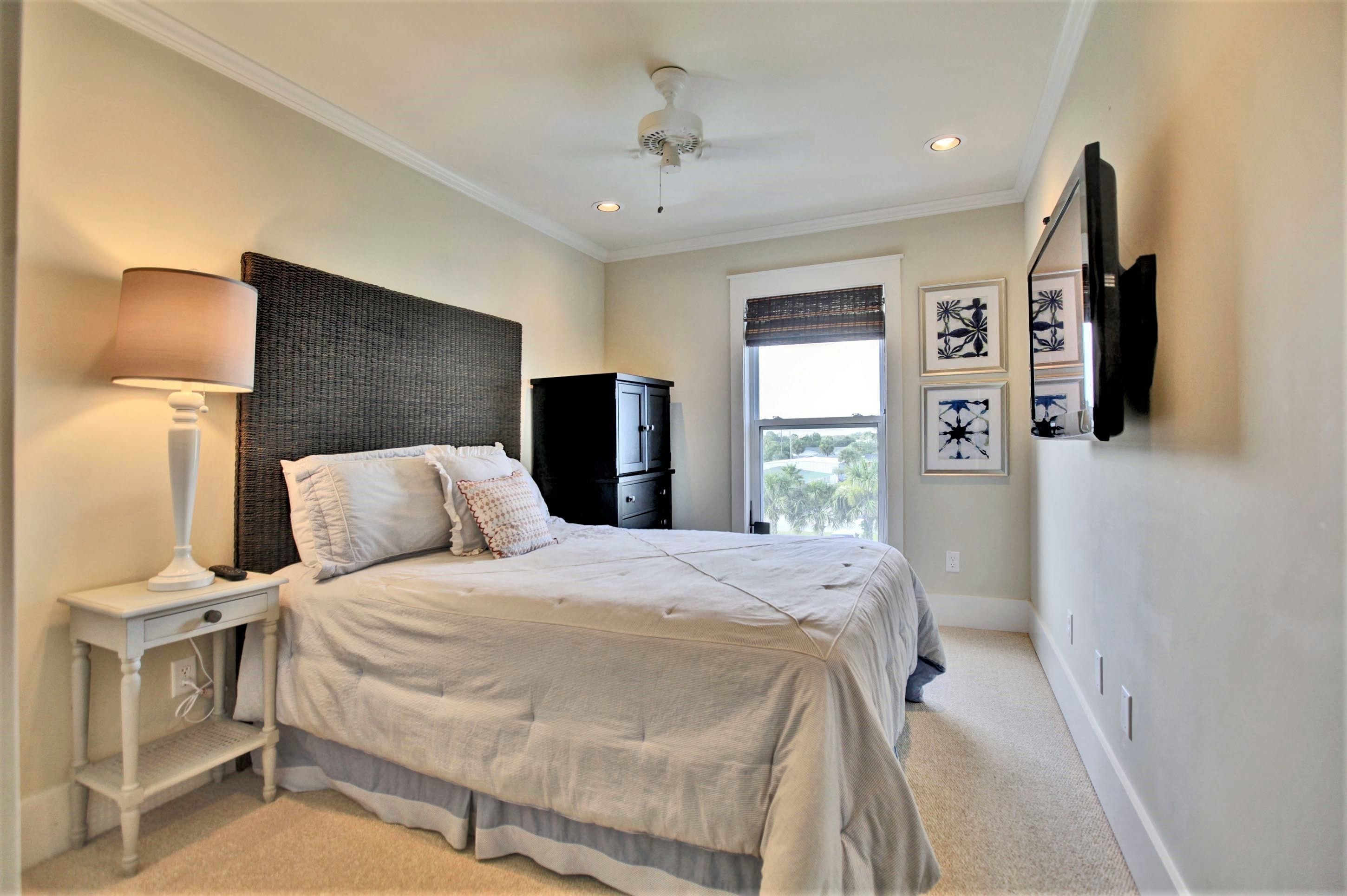 A bedroom with a bed, nightstand, lamp, wardrobe, and artwork on the wall.