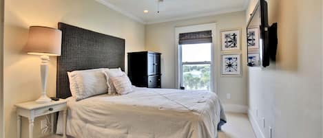 A bedroom with a bed, nightstand, lamp, wardrobe, and artwork on the wall.