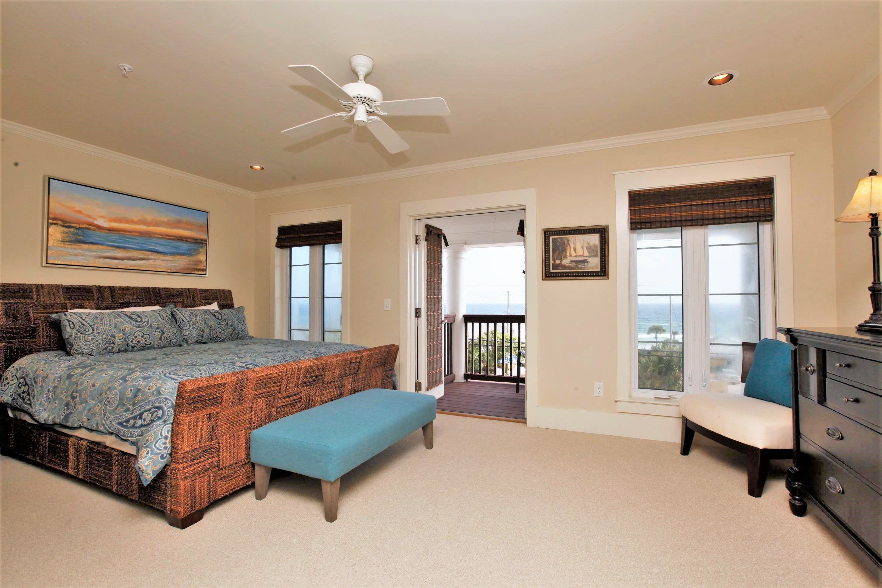 Quarto com cama, um banquinho, cômoda e varanda com vista.