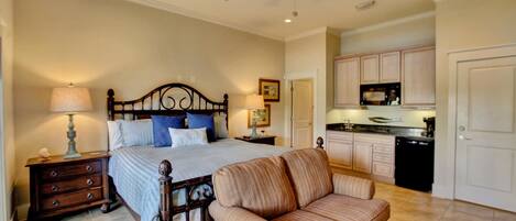 A bedroom with a bed, nightstand, lamp, and a sofa.
