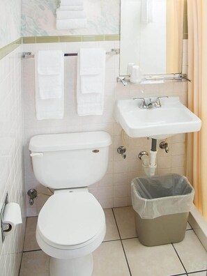 A standard bathroom with a toilet, sink, and trash bin.