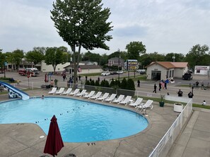 A swimming pool with lounge chairs, a red umbrella, and a flagpole with an American flag.