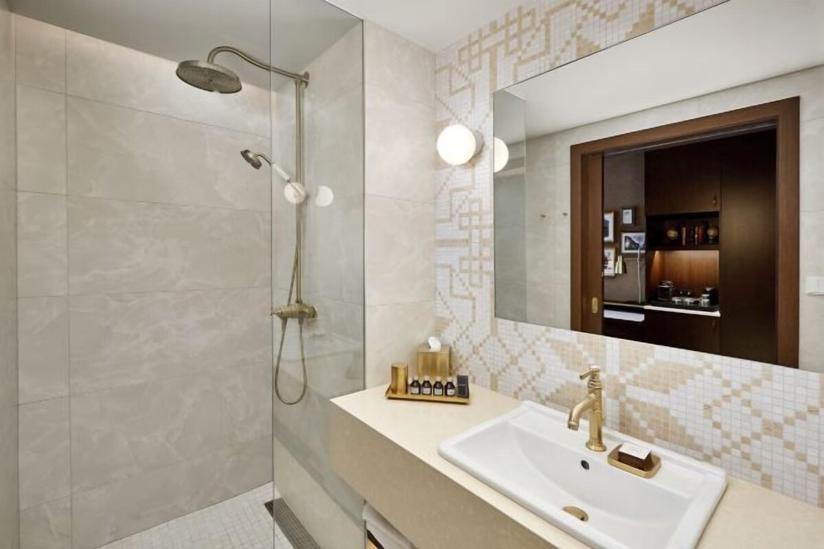 A modern bathroom with a walk-in shower, a vanity with a large mirror, and a tiled backsplash.
