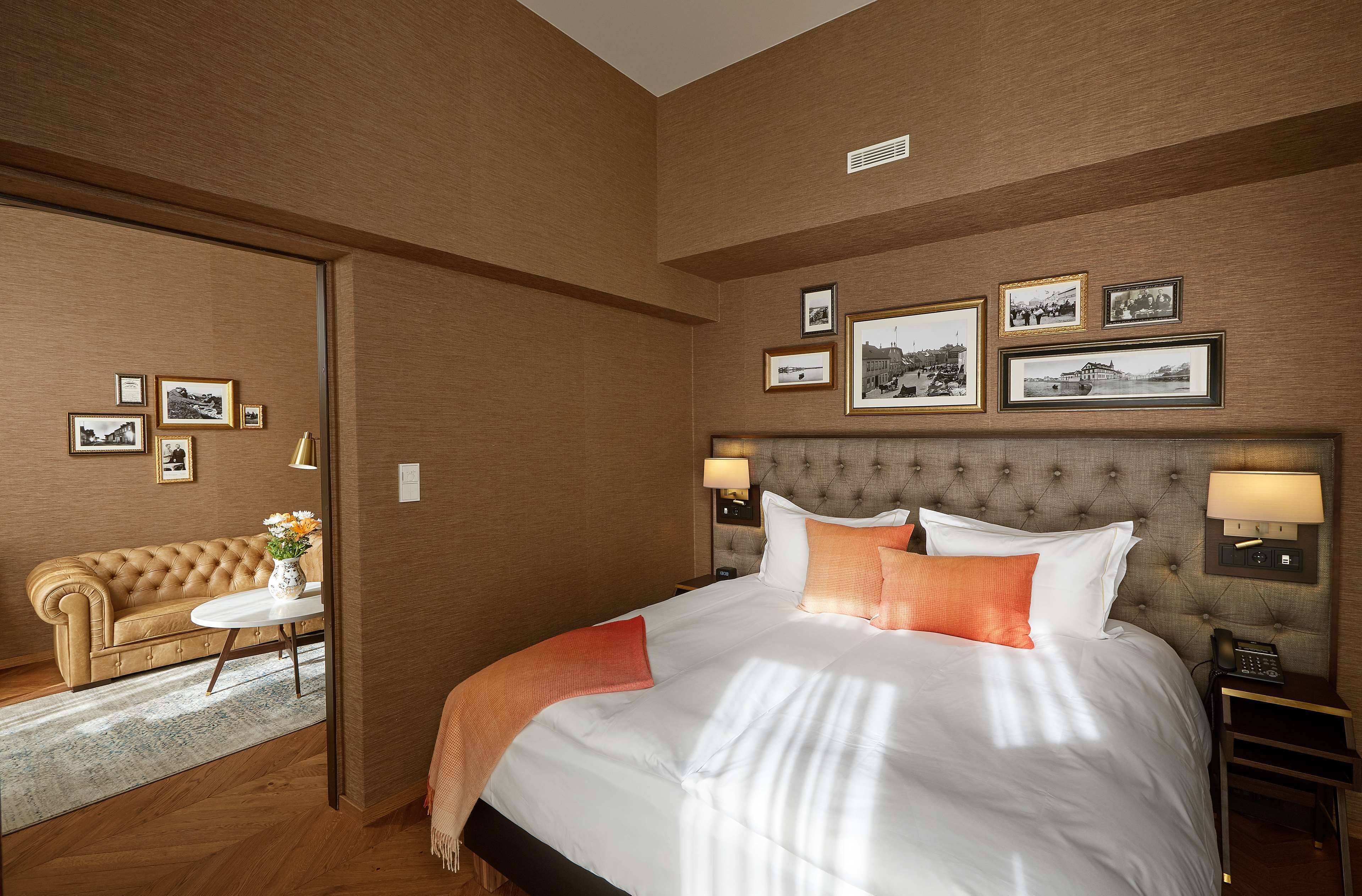 Una habitación de hotel con una cama grande, un sofá, una mesita y cuadros enmarcados en la pared.